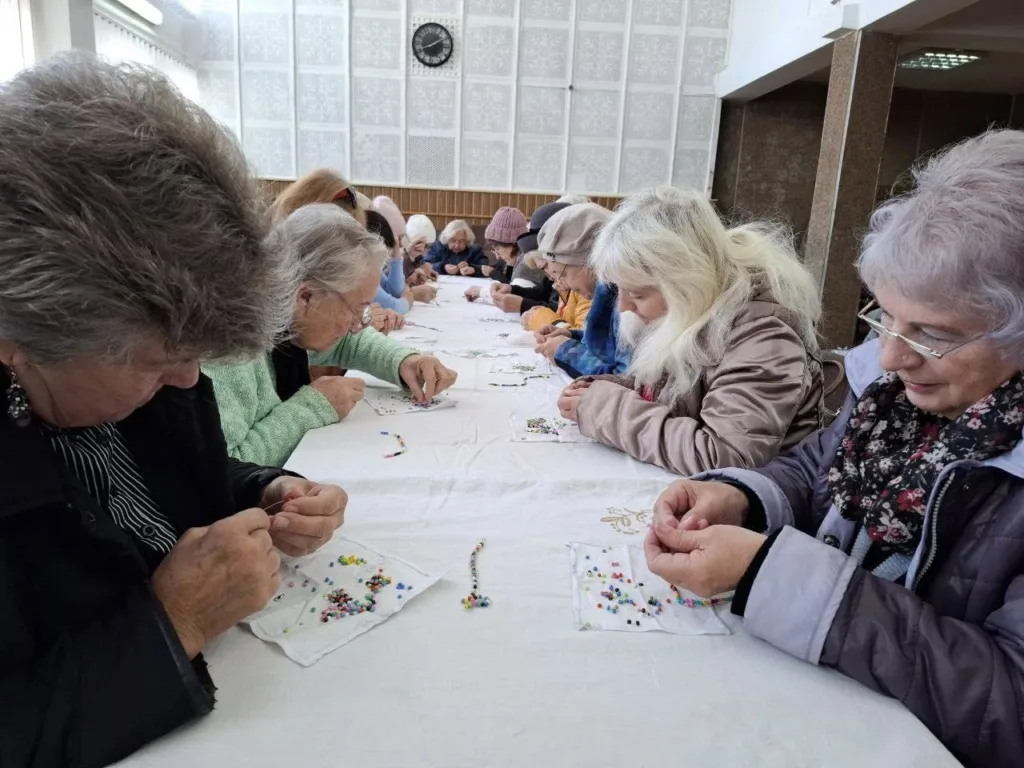 Люди займаються рукоділлям із кольоровими намистинами.