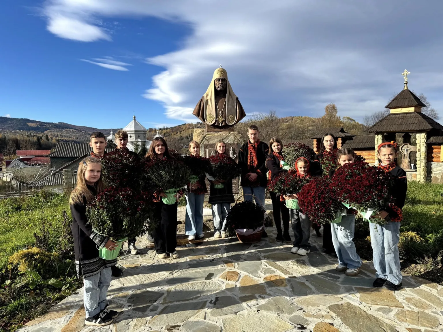 Діти з квітами біля пам’ятника у горах