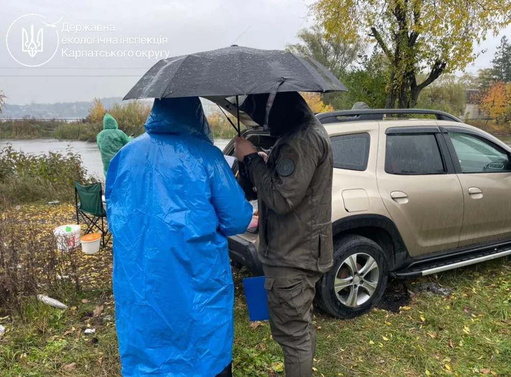Екоінспектори проводять перевірку біля річки під дощем