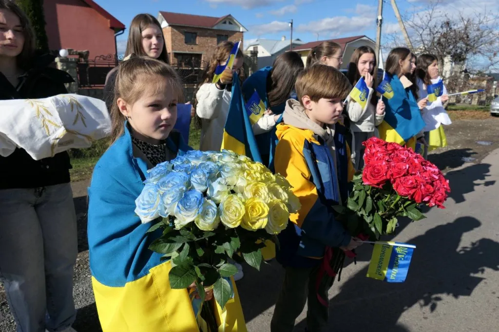 Діти з українськими прапорами та квітами на вулиці