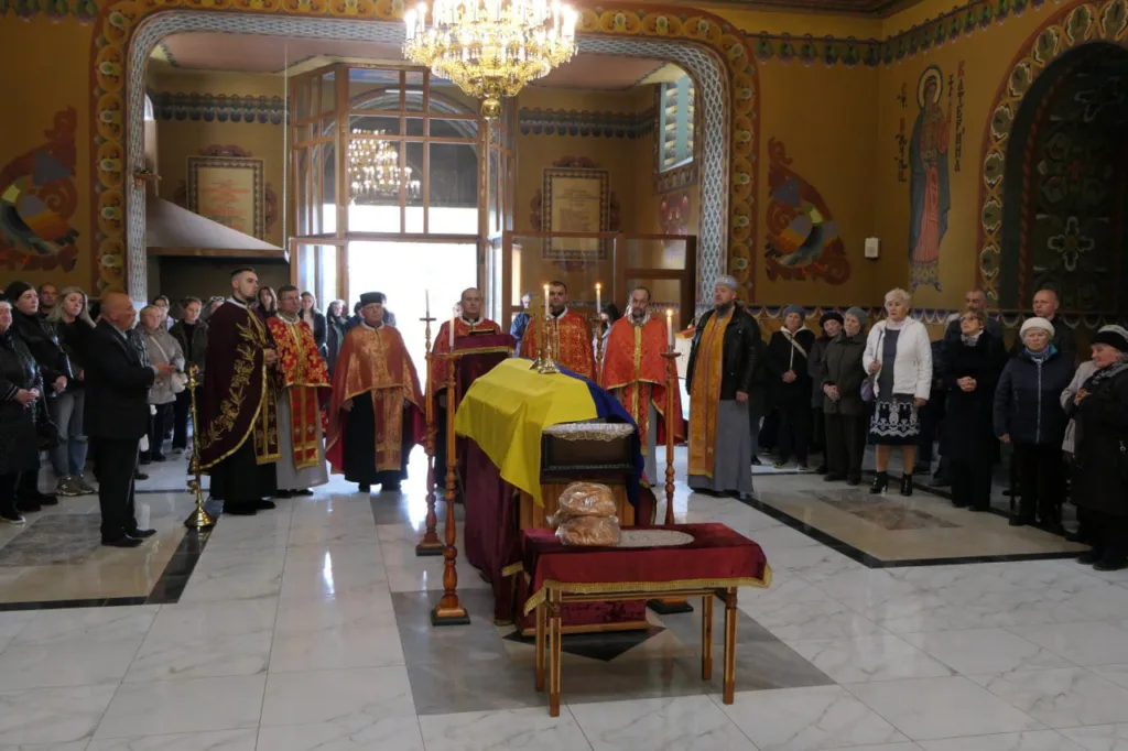 Прощання у церкві з труною, накритою прапором