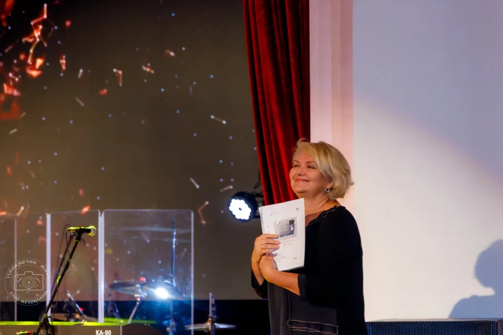 Жінка на сцені тримає документ під час події