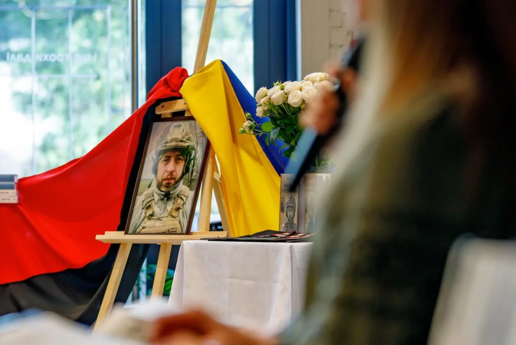 Фотографія військового біля прапорів на заході пам'яті