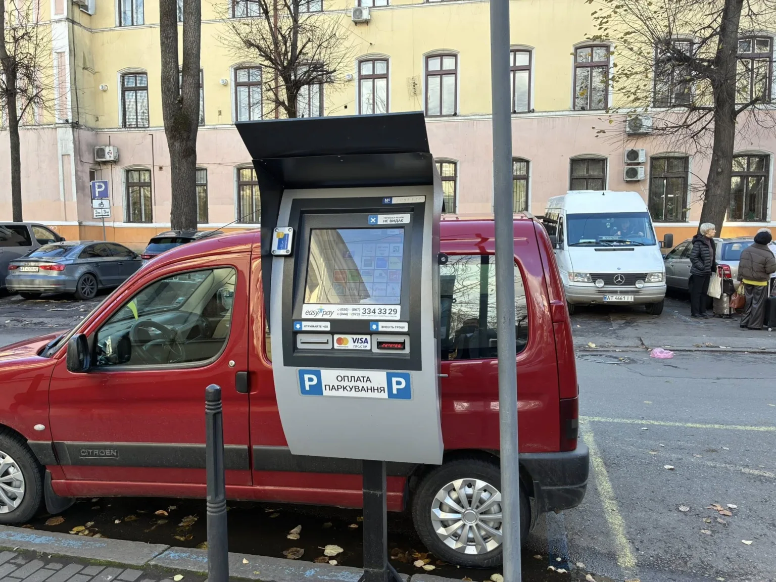 Паркомат біля червоного автомобіля на вулиці