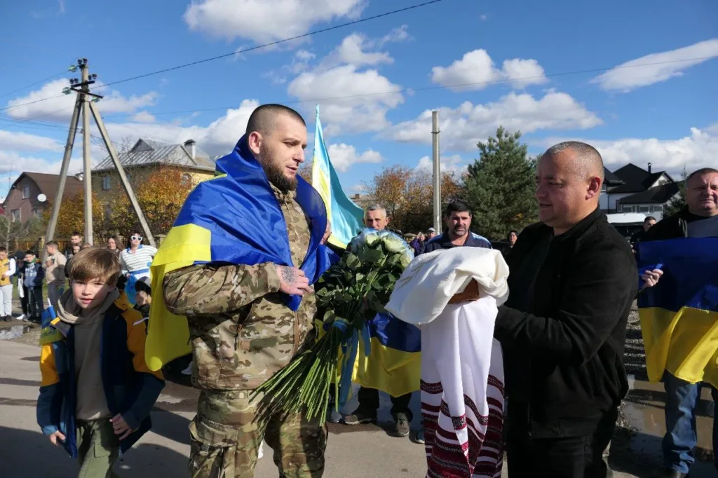 Зустріч військового з прапором України та квітами