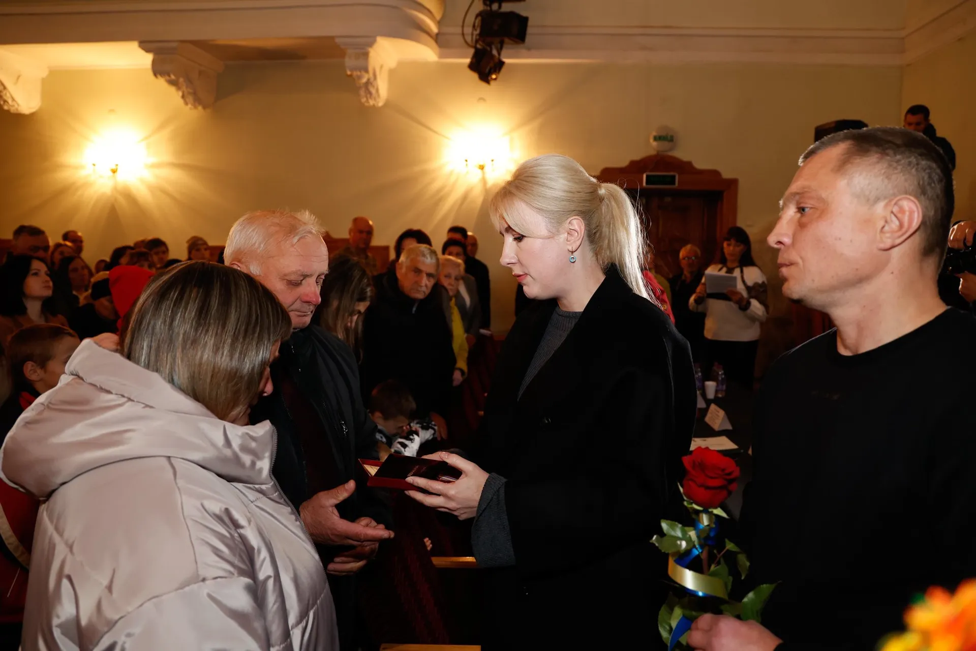 Вручення нагороди жінкою літньому чоловіку та жінці