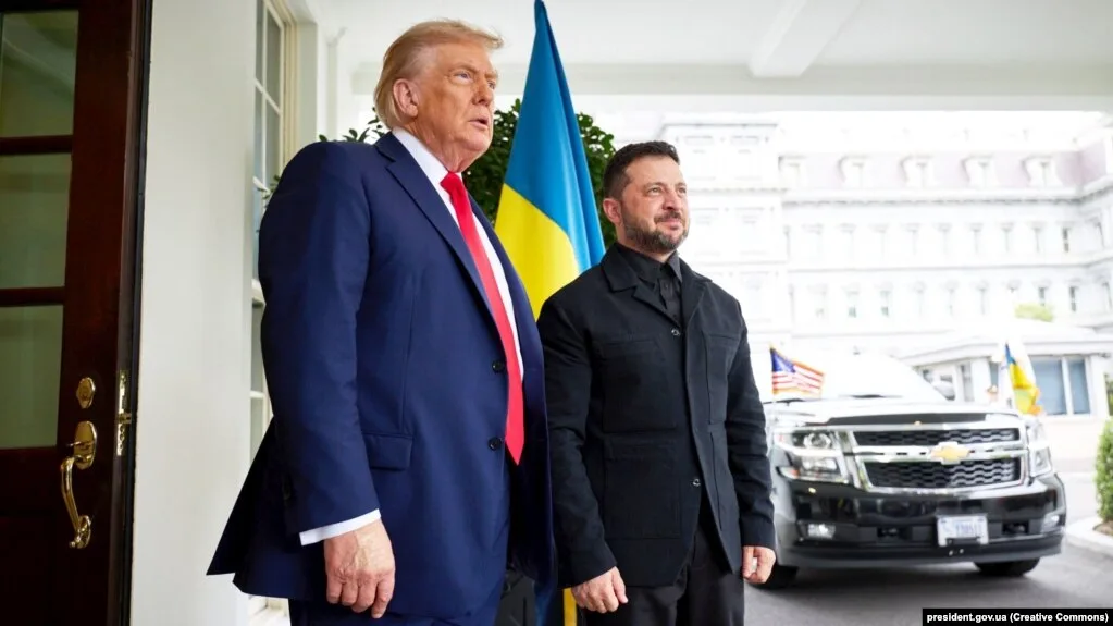 Двоє чоловіків стоять перед будівлею з прапором України