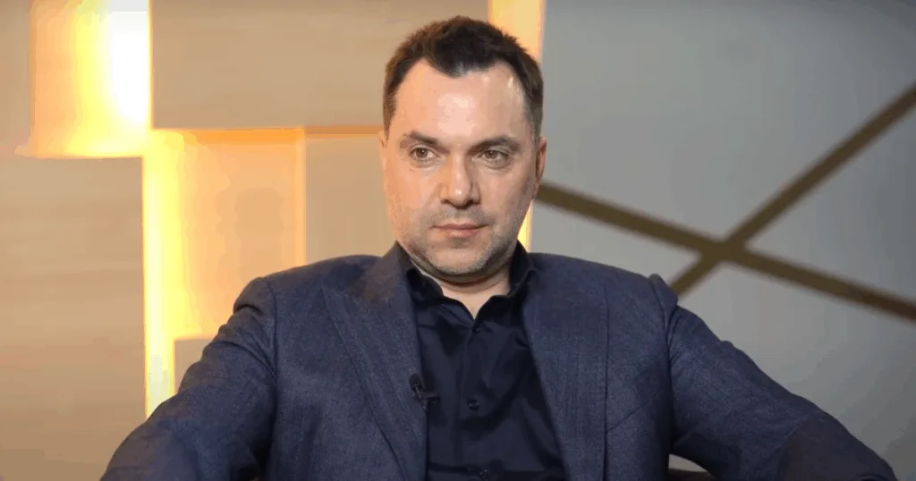 Чоловік у темному костюмі сидить у студії