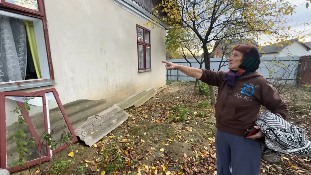 Жінка показує на стіну будинку восени