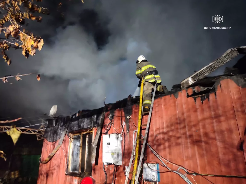 Пожежник гасить вогонь на даху будинку