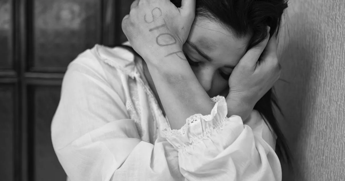 Жінка з написом «стоп» на руці плаче