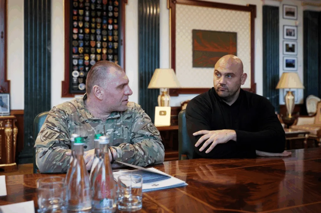 Двоє чоловіків обговорюють справи за столом