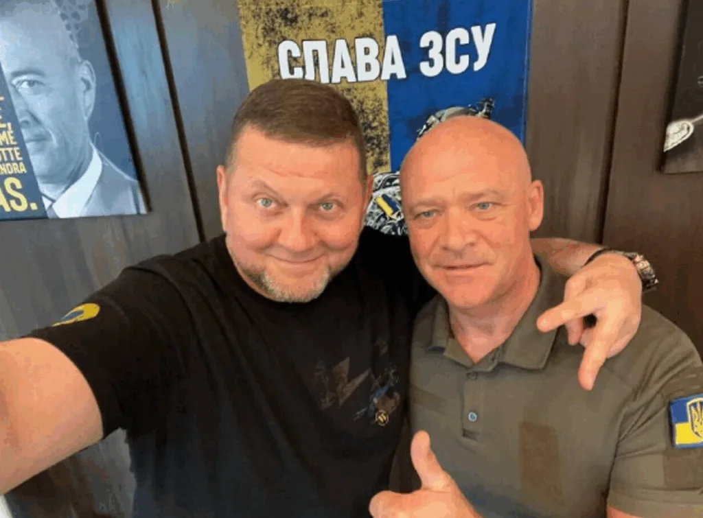 Двоє чоловіків перед плакатом Слава ЗСУ
