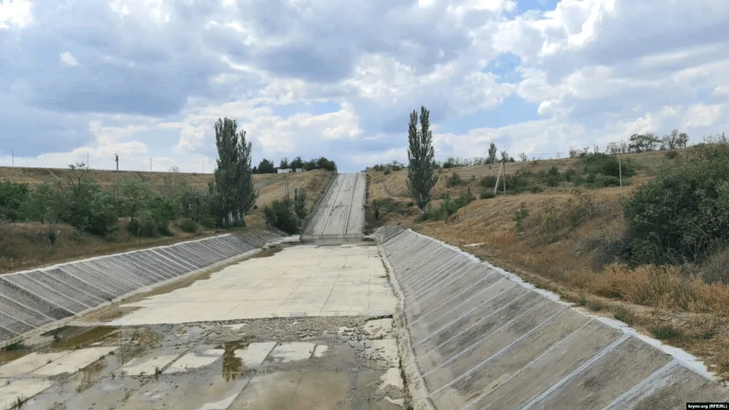 Сухий бетонний канал серед пагорбів і дерев