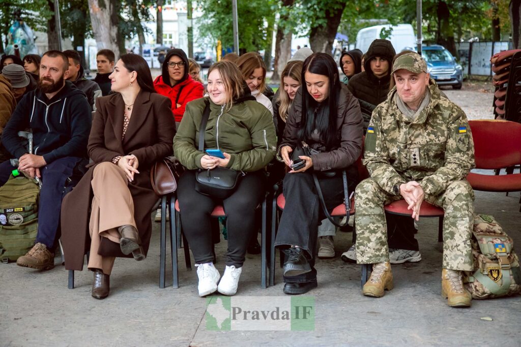 Люди сидять на стільцях під деревами на вулиці.