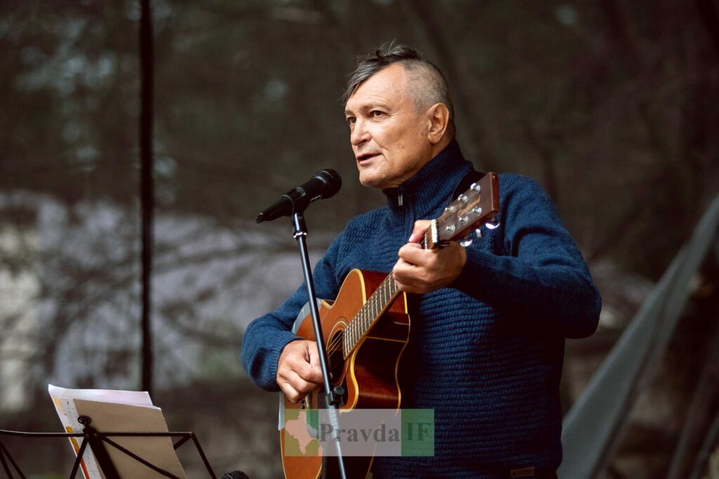 Чоловік грає на гітарі і співає на сцені.