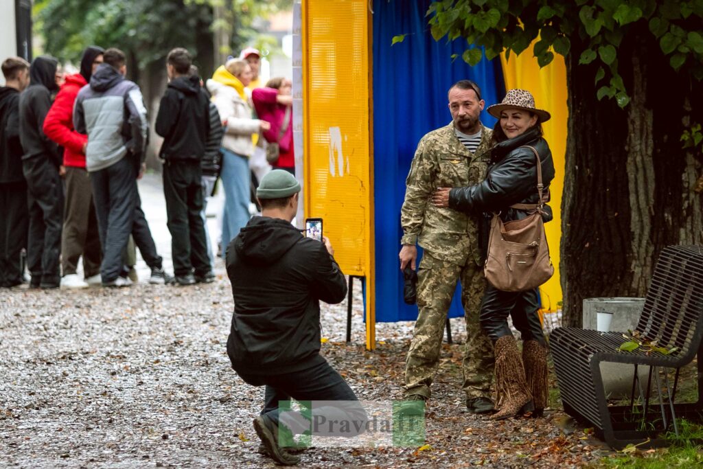 Люди біля виборчої дільниці, жінка обіймає чоловіка.
