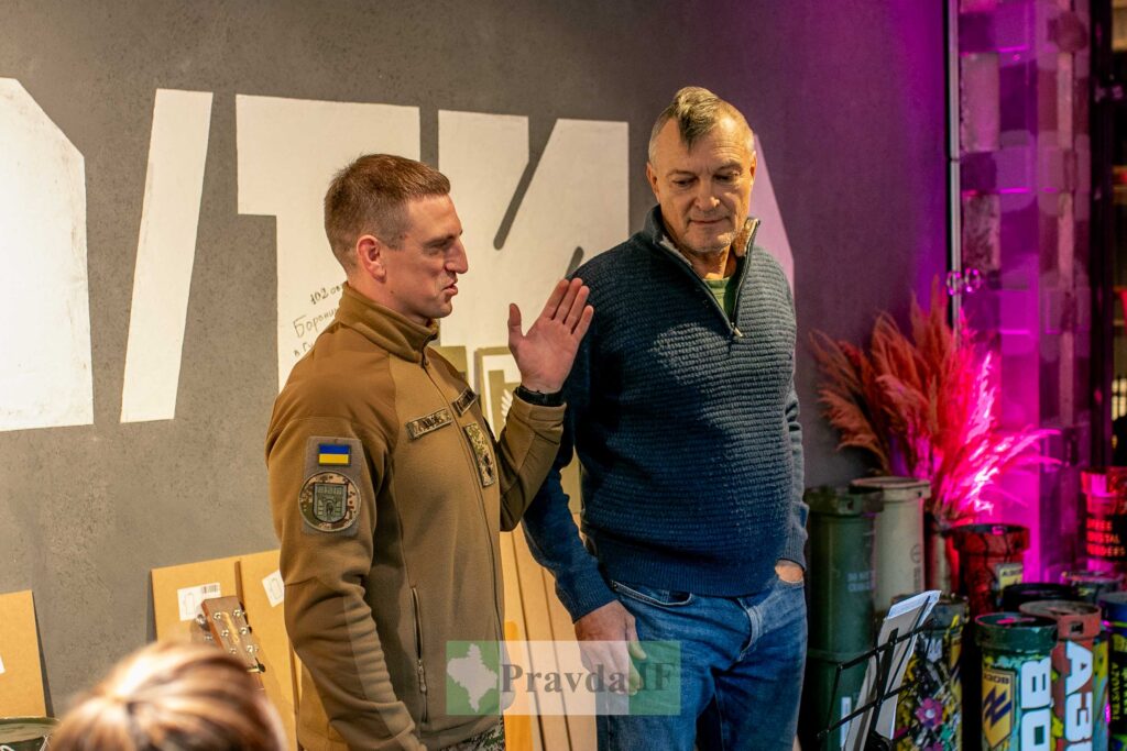 Чоловік в українській формі говорить з іншим чоловіком.