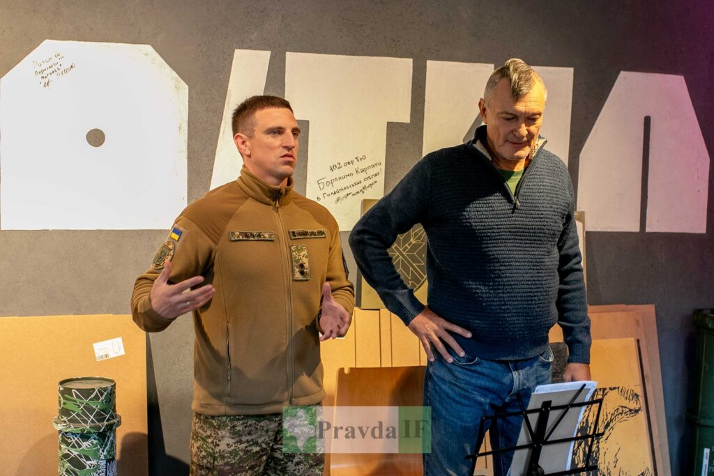 Військовий і чоловік на фоні написів стіни.