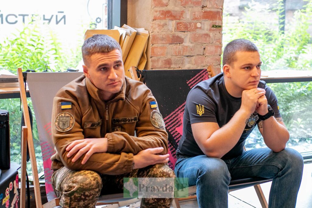 Двоє чоловіків у військовому одязі сидять в кімнаті.