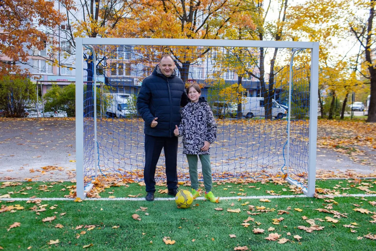 Двоє людей стоять біля футбольних воріт восени