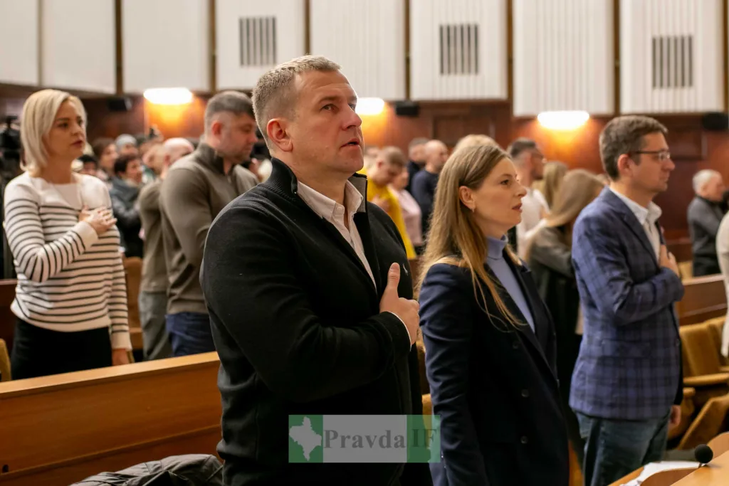 Люди стоять під час засідання в залі