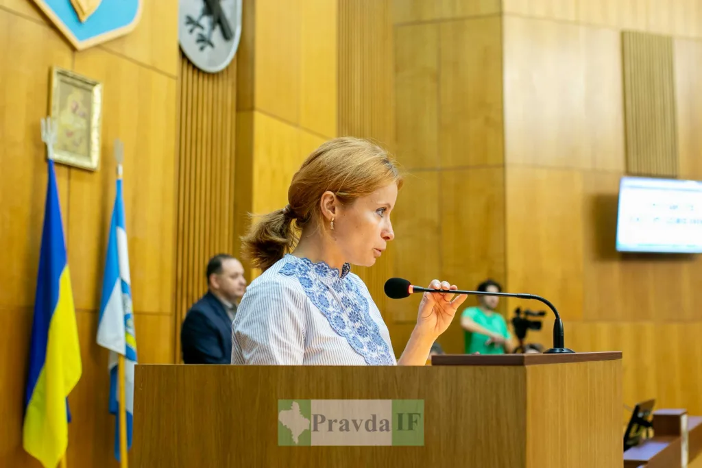 Жінка виступає на трибуні у залі засідань