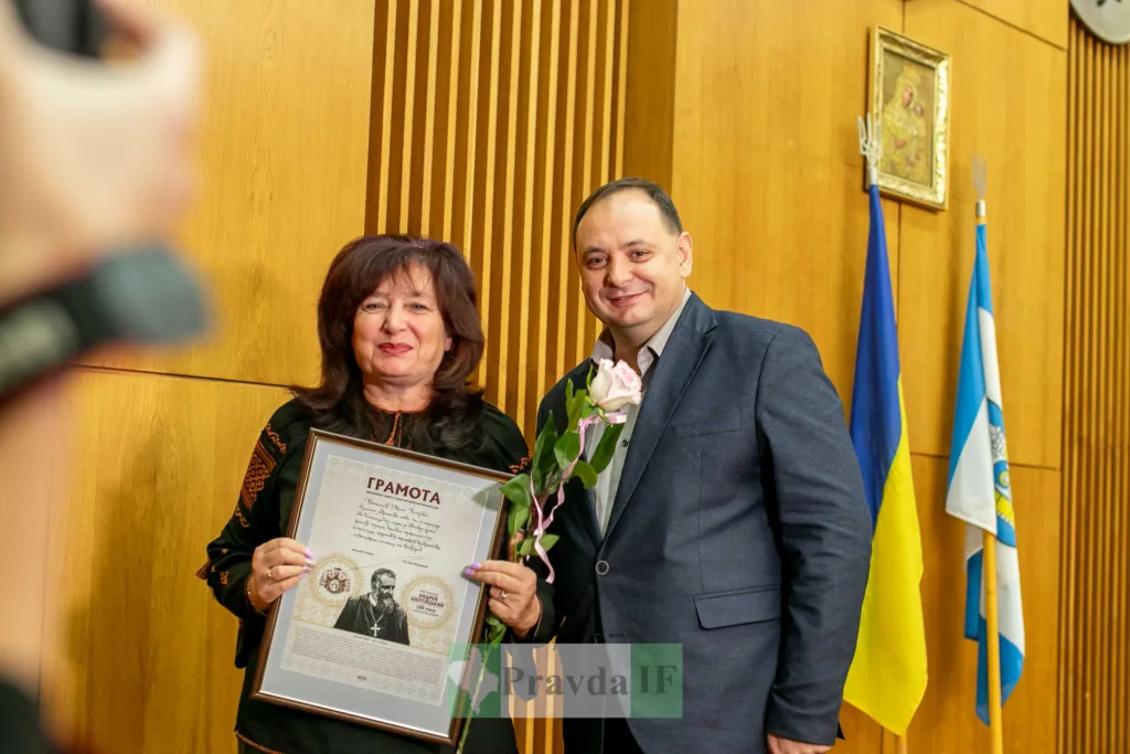 Жінка отримує грамоту в урочистій залі