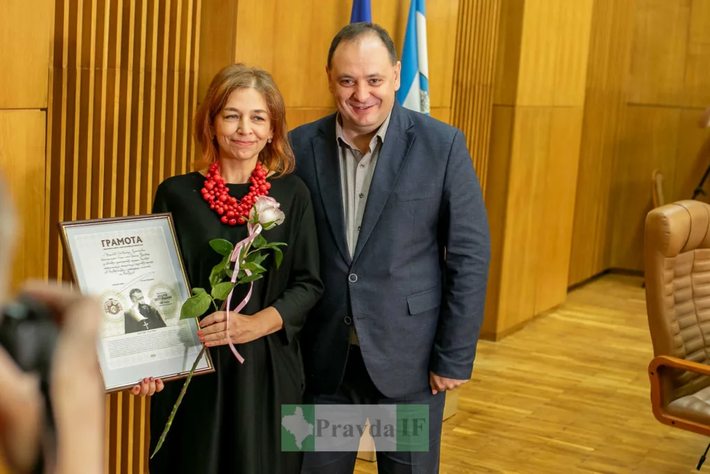 Жінка отримує грамоту та квітку на церемонії