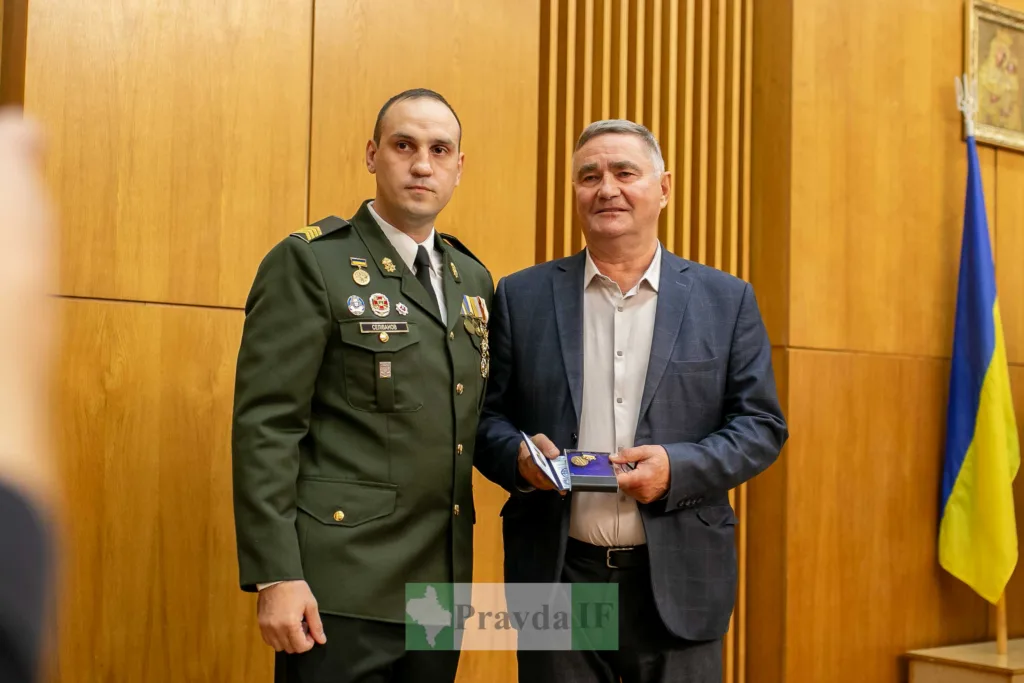 Військовий вручає нагороду чоловіку в залі