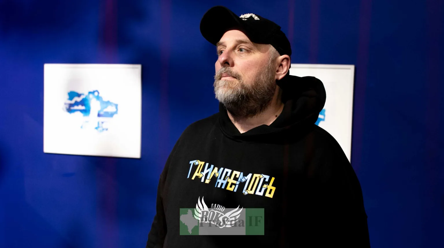 Чоловік у темному одязі на синьому тлі