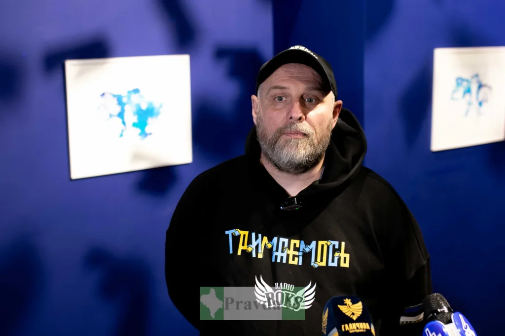 Чоловік у чорній толстовці дає інтерв'ю