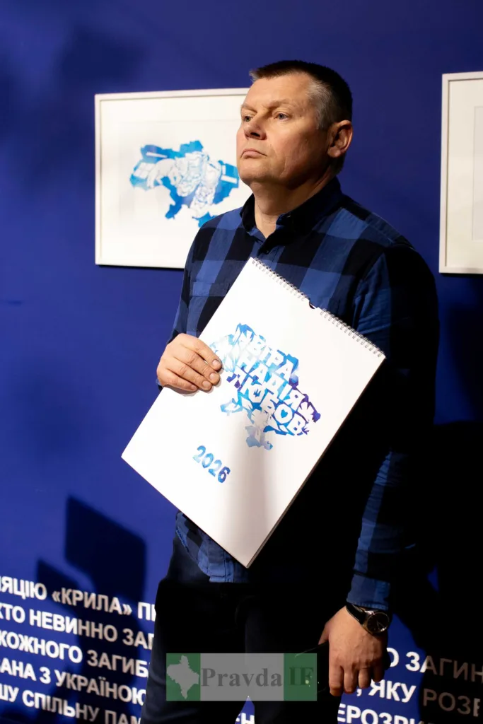 Чоловік тримає календар 2026 на фоні України