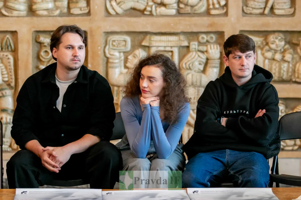 Троє людей сидять перед настінним мистецтвом