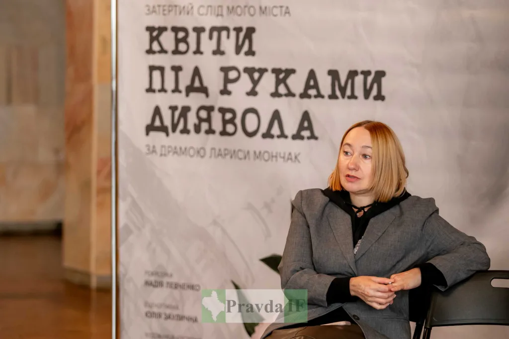 Жінка на тлі афіші вистави «Квіти під руками диявола»