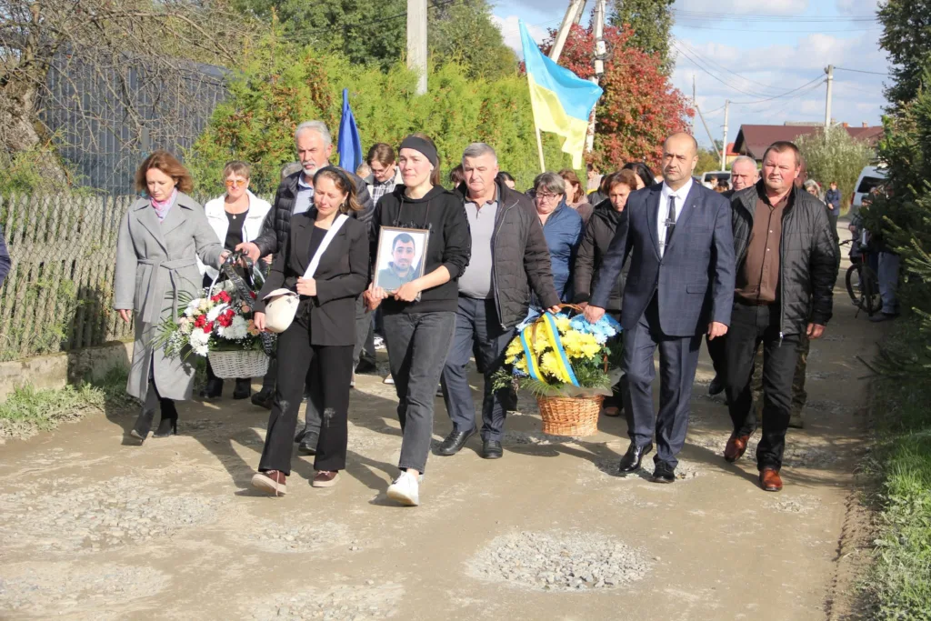 Люди несуть квіти та фото на похороні