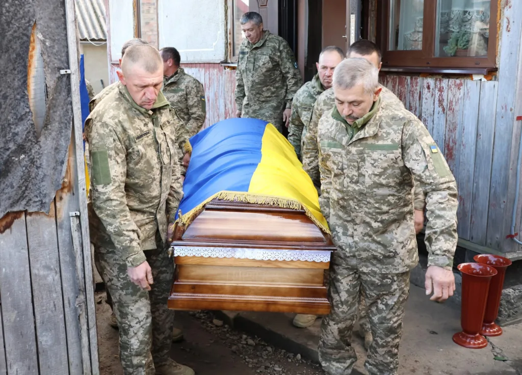 Військові несуть труну, накриту прапором України