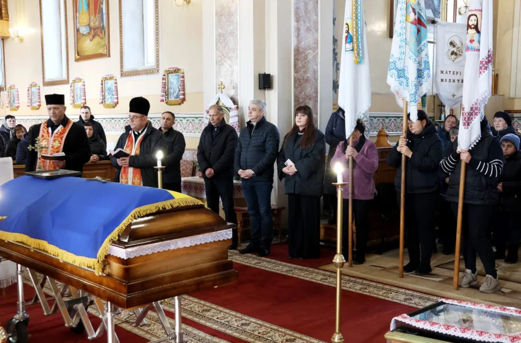 Похоронна церемонія у церкві з прапорами та труною