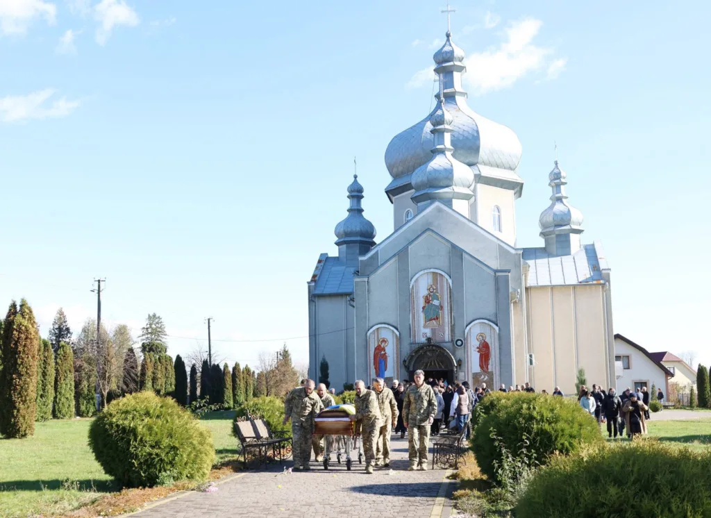 Військові несуть труну перед українською церквою
