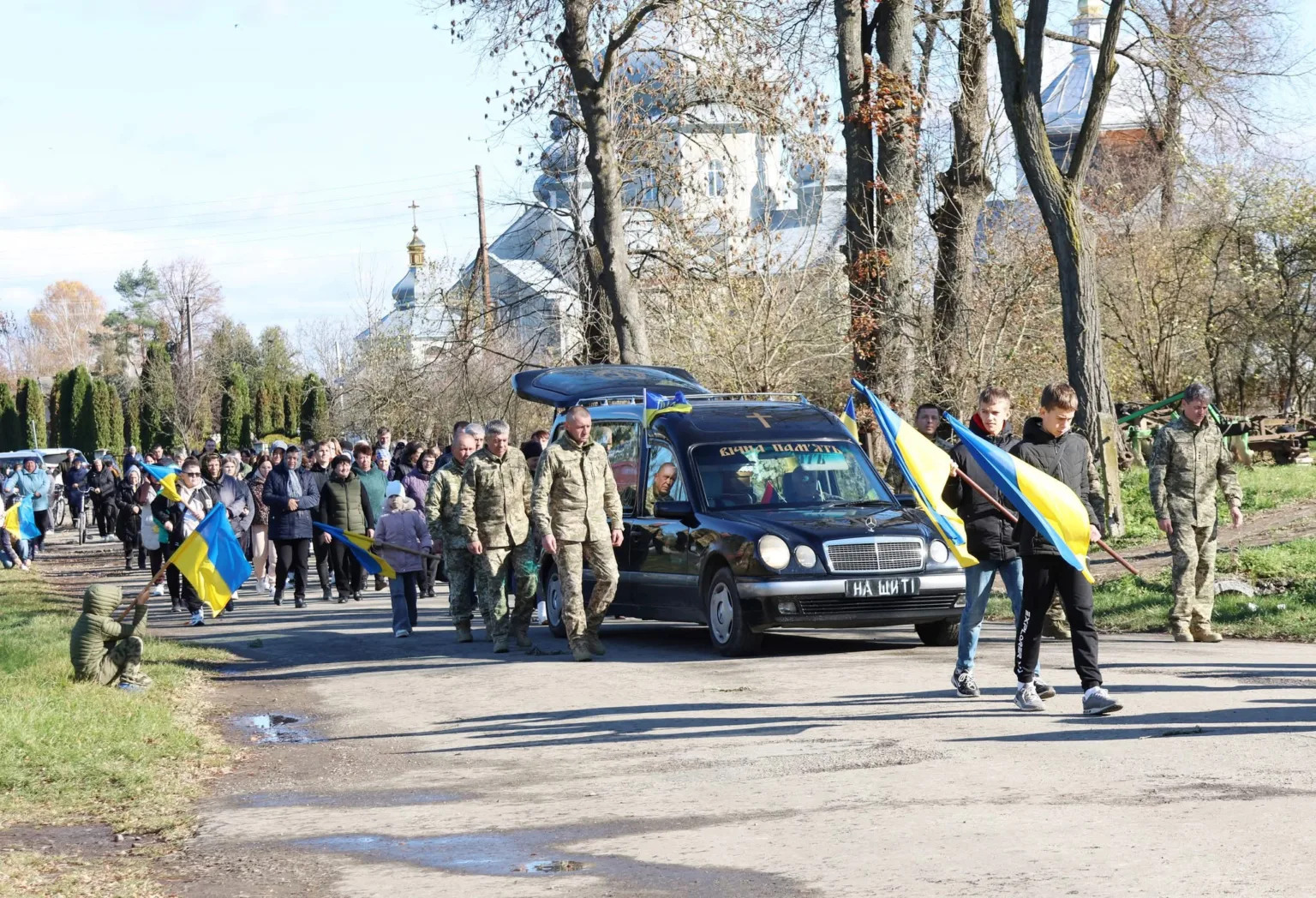 Похоронна процесія з українськими прапорами та військовими