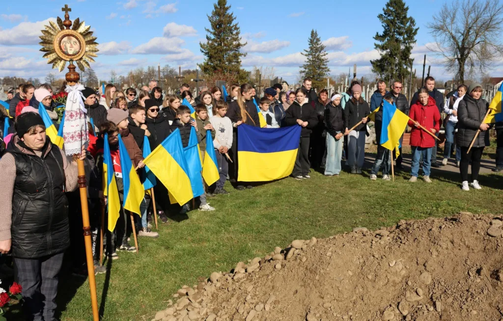 Люди з українськими прапорами на церемонії прощання