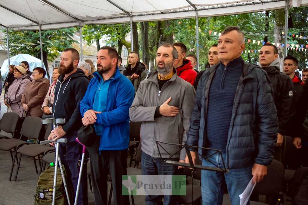 Група людей на заході у наметі, стоять уважно.