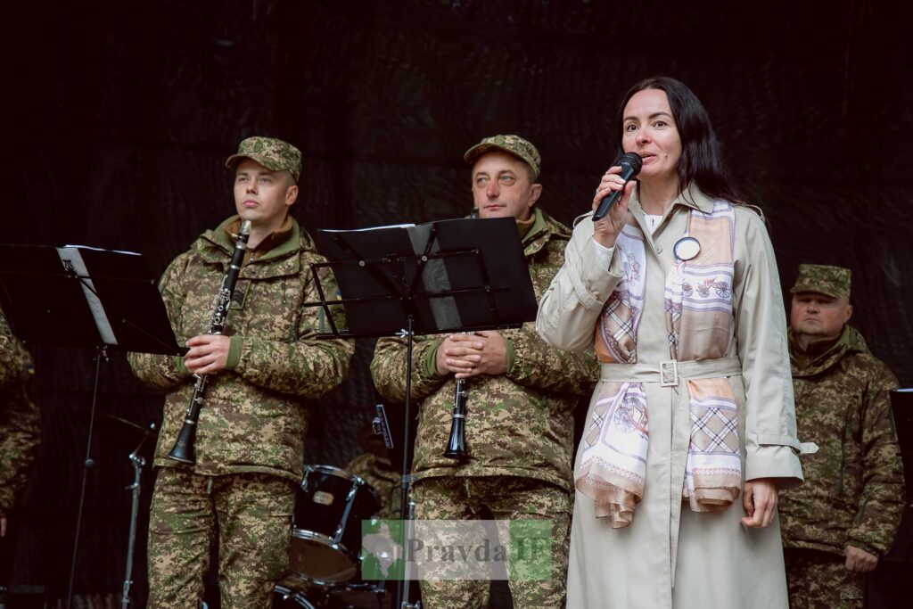 Жінка виступає перед військовими, тримаючи мікрофон.