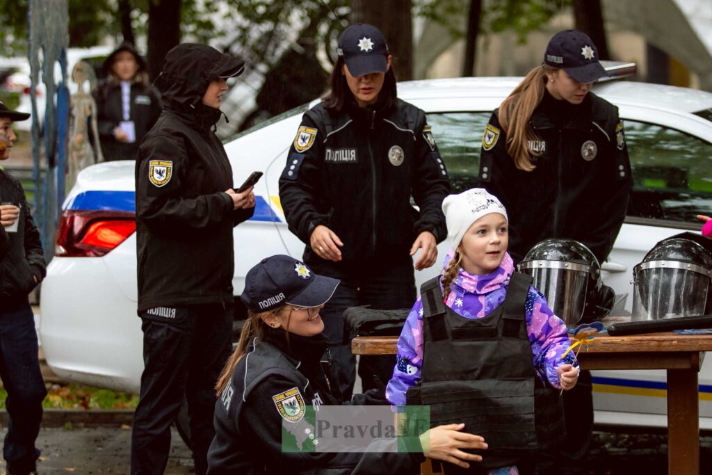 Поліцейські допомагають дитині приліпити поліцейську уніформу.