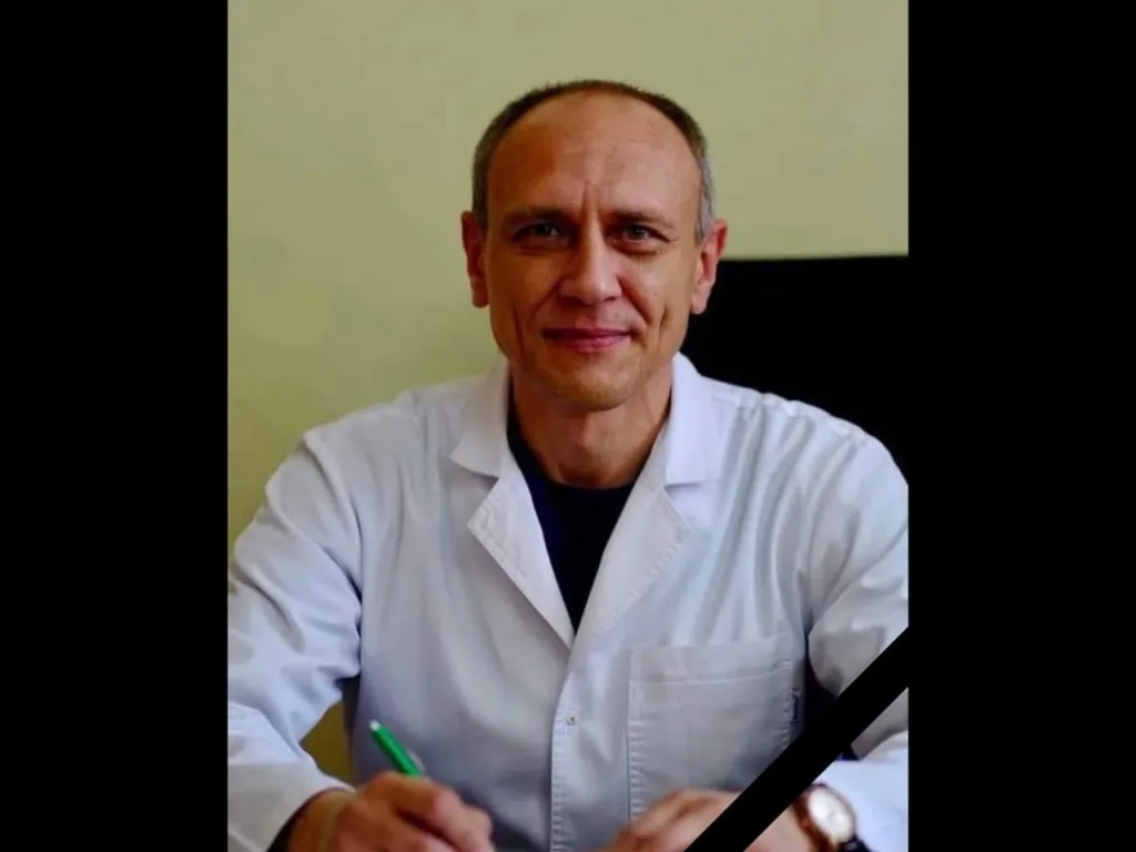 Усміхнений лікар у білому халаті сидить
