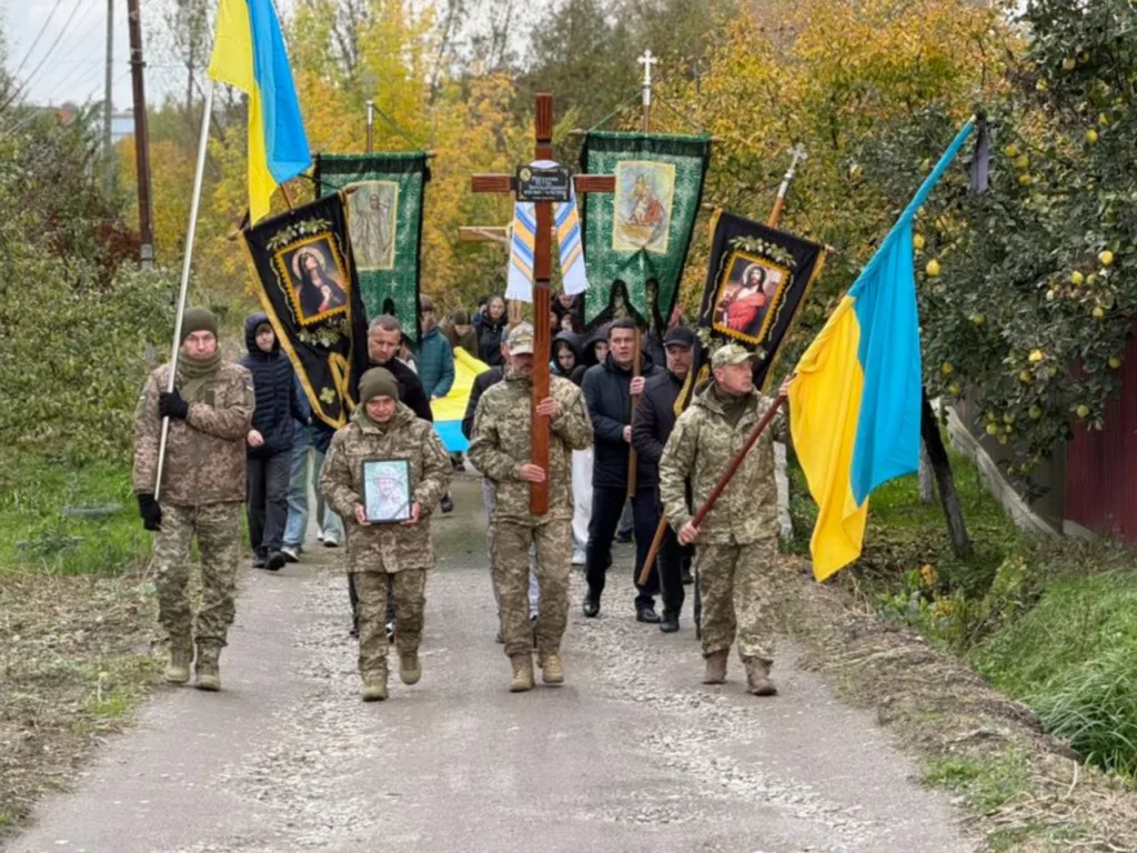 Військові несуть прапори та хрест у процесії
