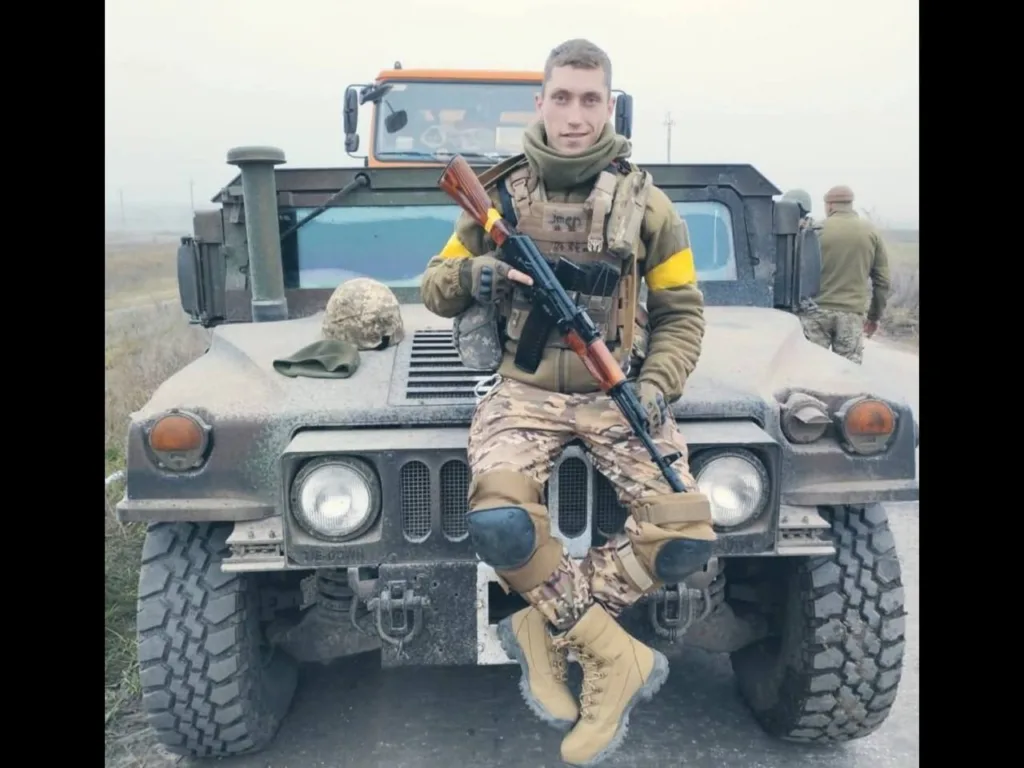 Військовий сидить на військовому позашляховику з гвинтівкою