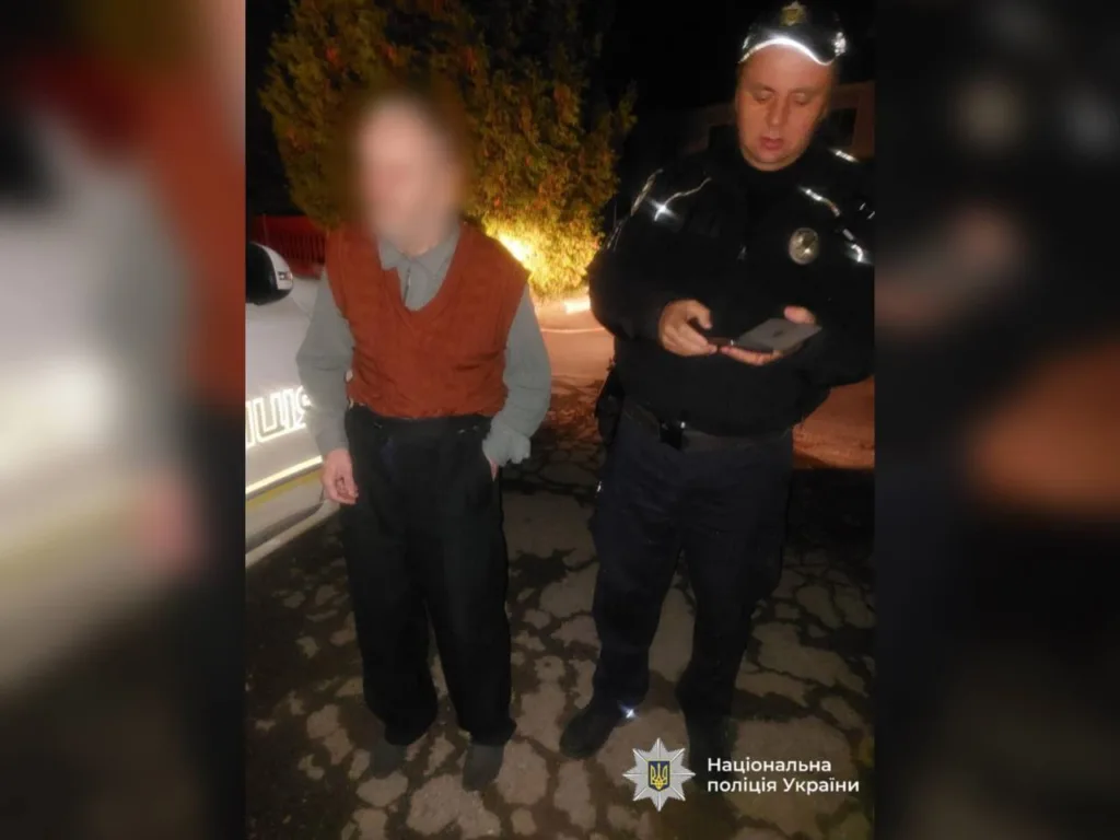 Поліцейський допомагає чоловіку на вулиці вночі