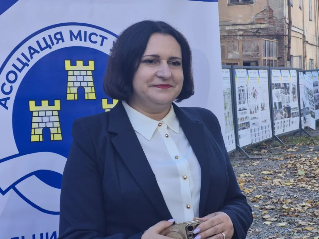 Жінка біля банера Асоціації міст України