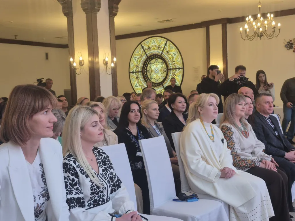 Люди на заході, жінки в вишиванках, фотографи знімають.